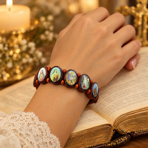 Red elliptical wooden saints bracelet worn on a wrist resting on a Bible